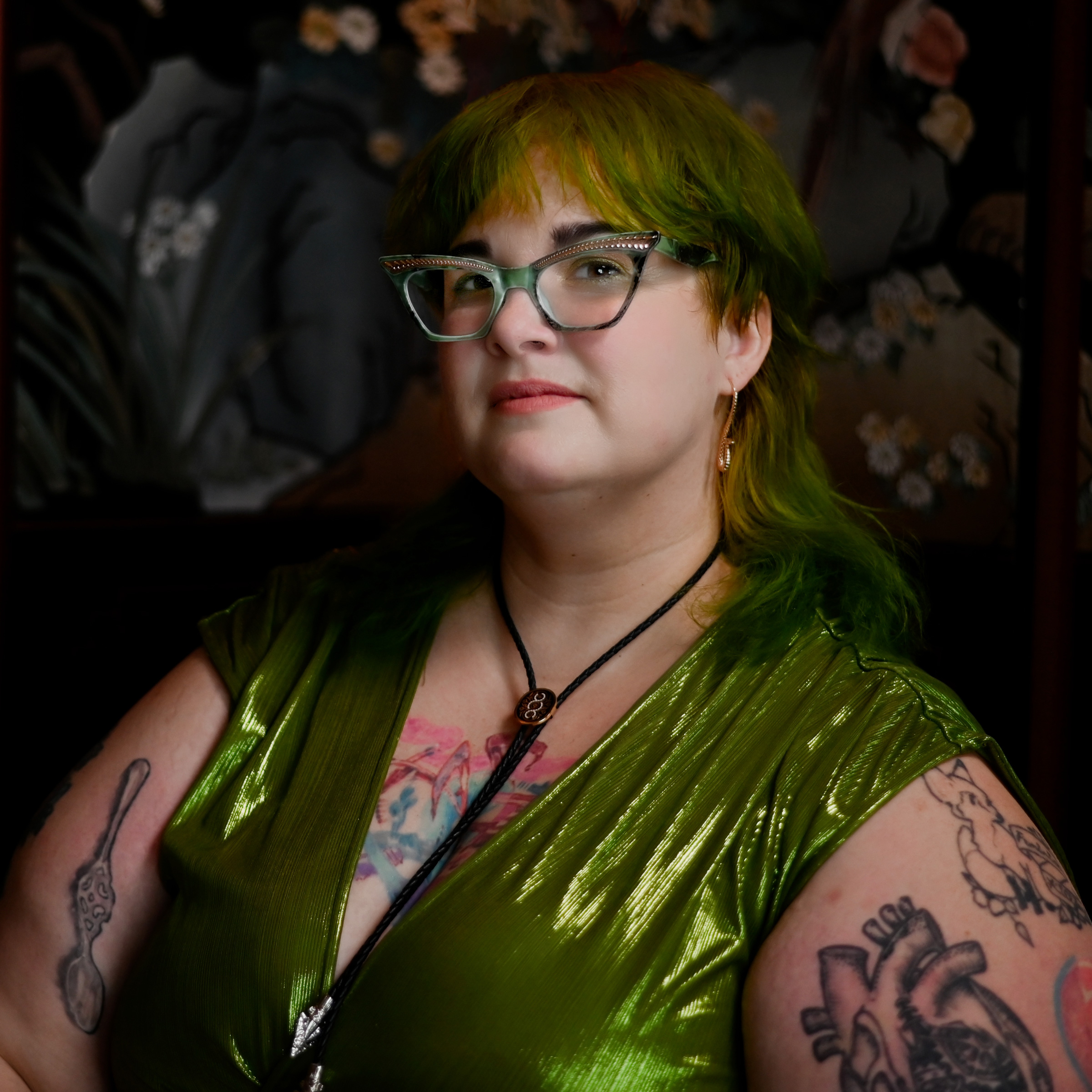 Headshot of Kitty Stryker in glasses and shiny green top.